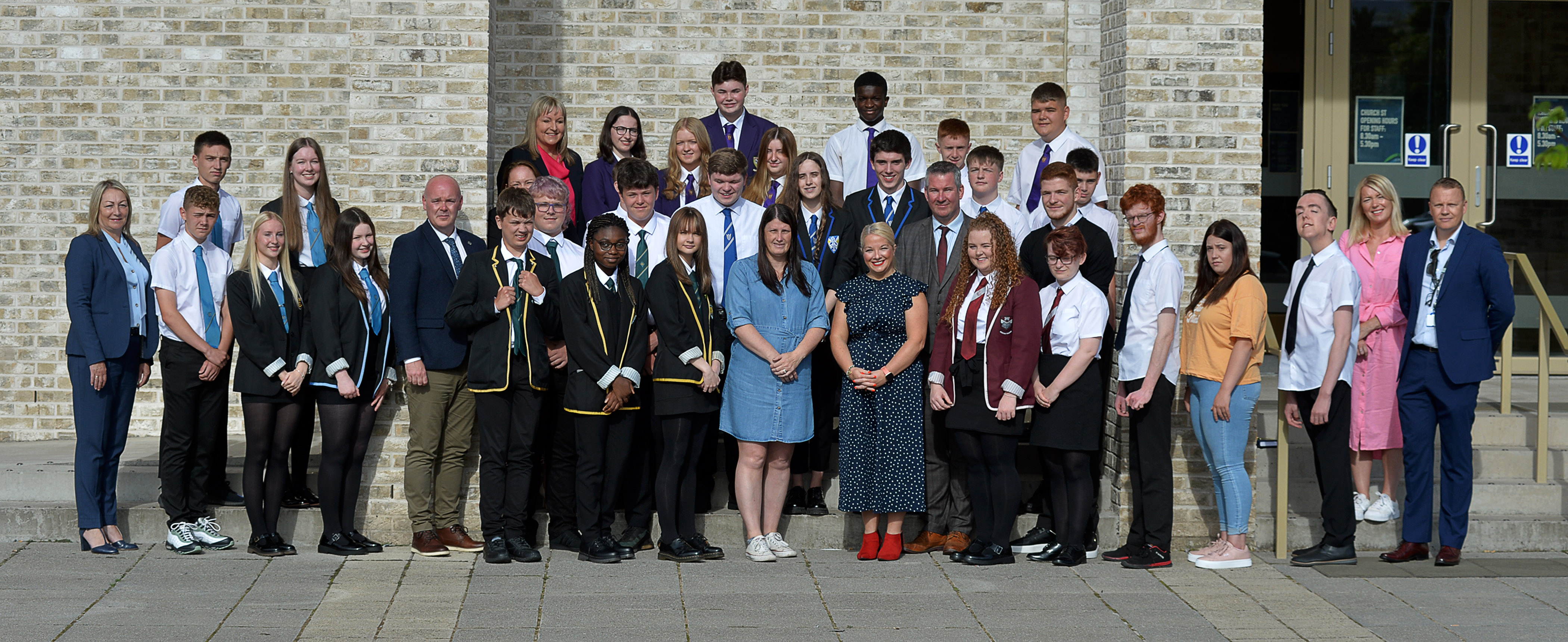 Pupils and teachers standing outside a school