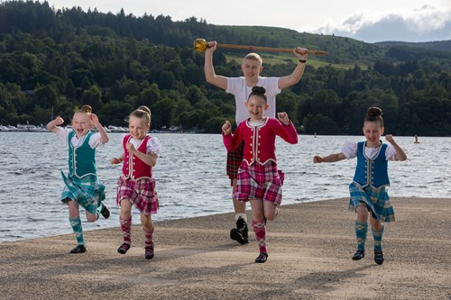 HIghland dancers running along pier at Loch Lomond